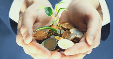 A hand is holding coins and a growing sprout representing mental health grants for nonprofits.